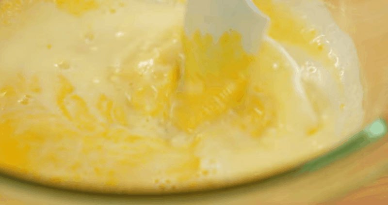 Sau khi phần sữa ấm nóng và bơ đã tan hết thì từ từ đổ sữa vào phần hỗn hợp lòng đỏ vừa đổ vừa khuấy đều.